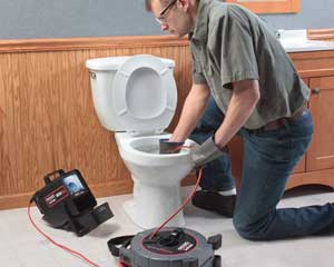 Todd is using a video camera to check a clogged toilet